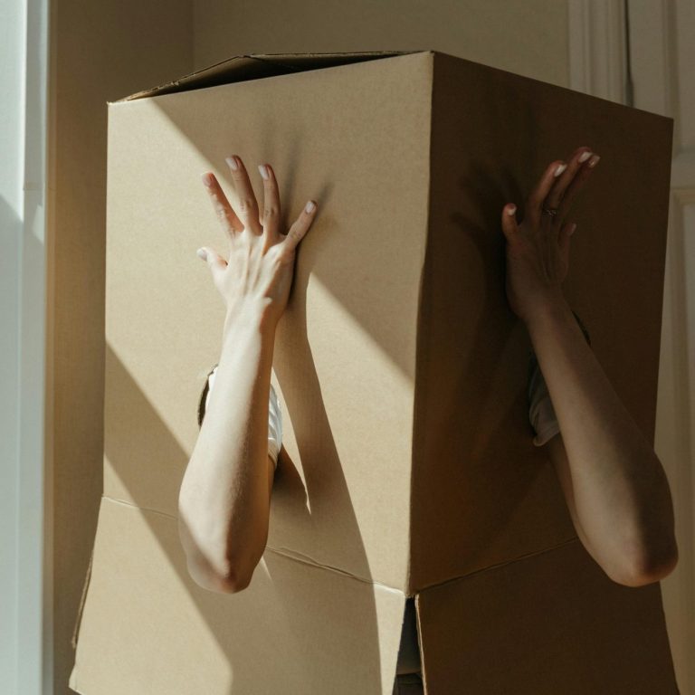 Person stuck inside a cardboard box looking to make positive changes.